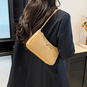 Sac sous le bras beige chic avec noeud doré porté par un mannequin élégant