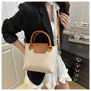 Close-up of contrast woven tote bag with brown leather strap and metal buckle