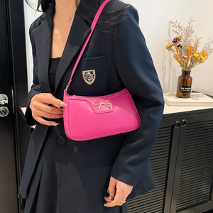 Sac à bandoulière rose avec boucle nœud doré porté par un mannequin élégant