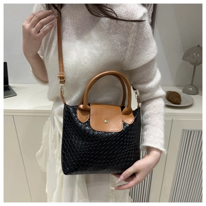 Detail of two-tone woven leather tote with brown flap and metallic round buckle closure