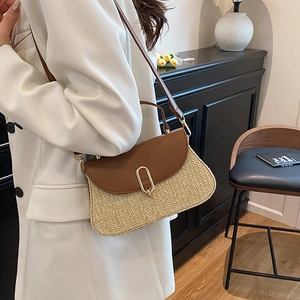Chic woven straw crossbody bag with brown leather flap and golden U-lock on white suit