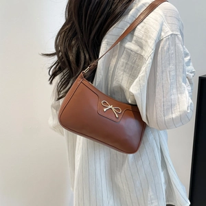 Détail du sac sous le bras en cuir marron avec une boucle noeud dorée vintage