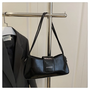 Detail of glossy black shoulder bag featuring polished texture and white logo branding