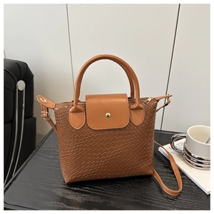 Detailed view of woven leather texture on a brown tote bag with gold magnetic buckle