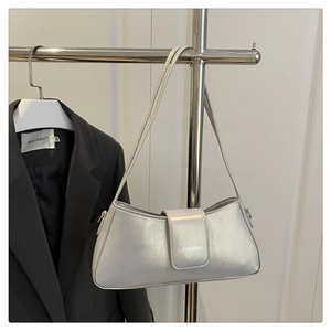 Detail of silver faux leather baguette bag with textured finish and brand logo lettering