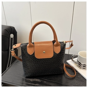 Detail of color-block tote bag featuring black woven fabric and brown faux leather trim