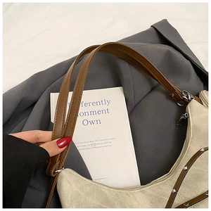 Detail of beige canvas tote with brown leather strap and silver metal rivets decoration