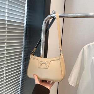 Détail du sac beige avec un ornement de nœud en métal argenté poli sur cuir souple