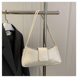 Detail view of cream baguette bag with dual slim straps and brand lettering logo