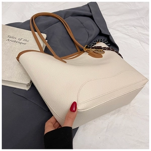 Close-up of off-white lychee texture tote bag with braided rope and gold key charm