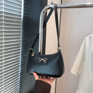 Détail du nœud doré en métal et de la fermeture éclair fleur sur sac à main noir
