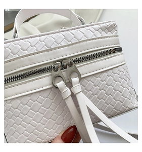 Détails de la texture tissée et des zips argentés sur un sac à main blanc rigide