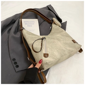 Detail view of beige pleated tote bag with dark brown strap and small coin purse pendant