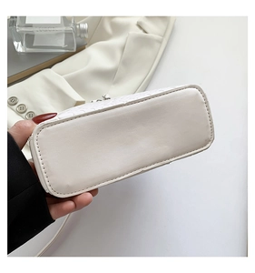 Vue détaillée de la base rectangulaire et de la texture en cuir tressé du sac à main blanc