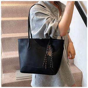 Close-up of black lychee texture tote bag with fashion embossing and tennis racket charm