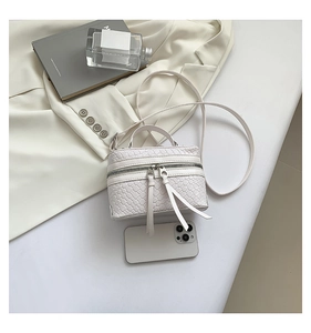 Détail du sac boîte blanc tressé avec de longs zips à glands et une poignée élégante