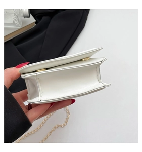 Close-up of white crossbody bag showing side accordion folds and gold chain strap