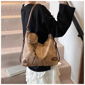 Close-up of brown vintage tote bag with small round coin purse and textured leather