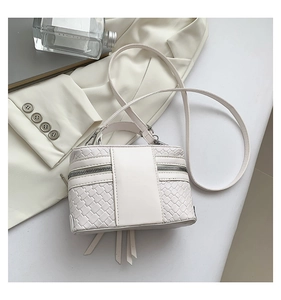 Détail de la texture tressée blanche d'un sac bandoulière rigide avec fine lanière