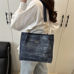 Minimalist navy denim tote bag with star pattern and gold chain strap shown on model