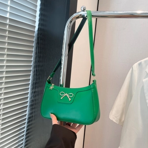 Détail du sac hobo vert avec noeud doré et tirette de fermeture en fleur