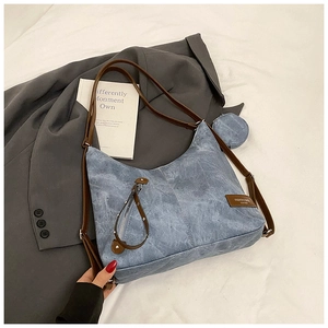 Detail of blue denim textured tote bag with brown straps and small round coin purse