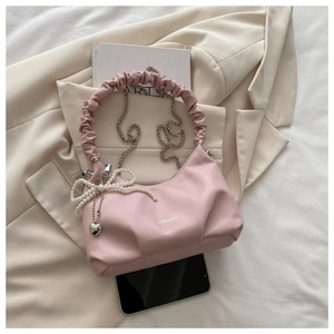 Detail of pink pleated cloud bag with pearl bow, heart pendant, and silver chain strap