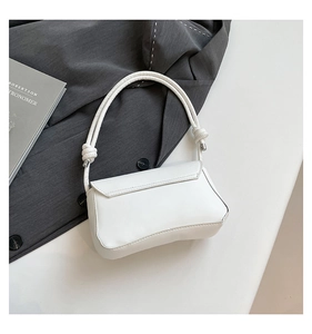 Detail of white leather baguette bag featuring unique knotted shoulder strap and silver hardware