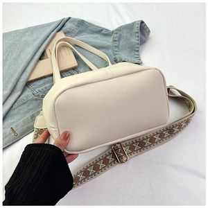 Close-up of white lychee texture faux leather bag with geometric pattern woven strap