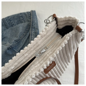 Close-up of cream corduroy tote bag featuring vertical texture and a dark leather logo tag