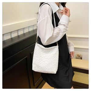 Close-up of white floral lace shoulder bag with elegant hollow texture and gold buckle