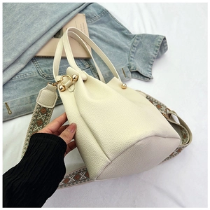 Close-up of cream lychee leather handbag with colorful woven strap and gold hardware detail
