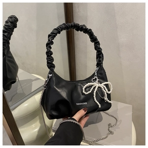 Detail view of black ruched cloud bag featuring pearl bow charm and chain strap