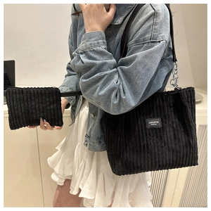 Detail of black corduroy tote bag set featuring leather chain strap and logo patch