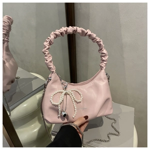 Detail of pink pleated handle bag with pearl bow charm and metal chain strap