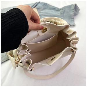 Detail of off-white lychee leather bucket bag showing magnetic closure and interior pocket