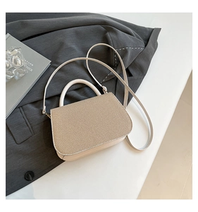 Détail de texture du sac à bandoulière beige sur fond de veste de costume gris