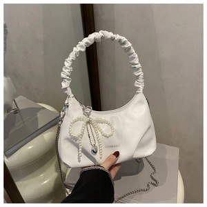 Detail of white ruched cloud bag with pearl bow charm and metal chain strap