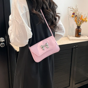 Pink minimalist crossbody bag with silver bow accent on smooth synthetic leather