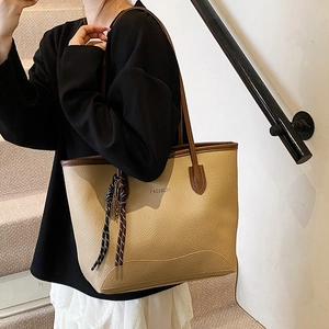 Minimalist beige tote bag with brown trim and fashion letter print in a model shot