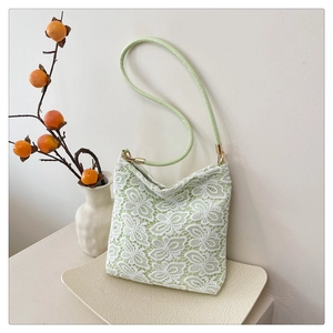 Detail of white butterfly lace floral pattern over a pale green shoulder tote bag