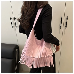Detailed view of a pink crossbody bag with long tassels on a shoulder-carried model