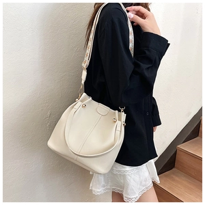 Detail of cream-white bucket bag with lychee grain leather and jacquard woven strap