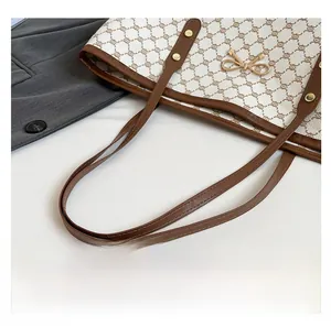 Détail du sac fourre-tout crème avec motif monogramme marron et boucle nœud doré