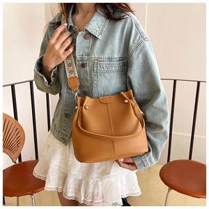 Close-up of caramel leather bucket bag with litchi texture and decorative metal studs