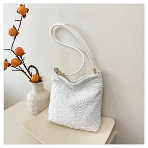 Close-up of white lace embroidered shoulder bag with floral patterns and gold hardware