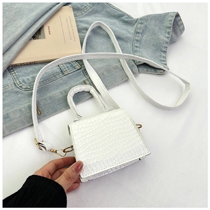 Dettaglio mini borsa bianca con motivo a coccodrillo, fibbie dorate e tracolla lunga