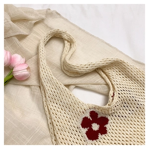 Détail d'un sac cabas en crochet crème orné de motifs floraux rouges brodés