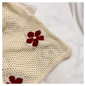 Vue détaillée de la maille crochetée beige avec broderie de fleurs rouges vibrantes