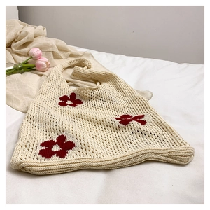 Détail du sac cabas en crochet crème avec motifs de fleurs rouges et texture tricotée
